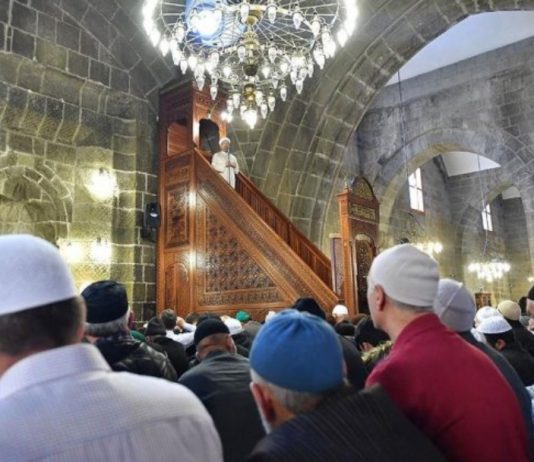 Nëse i bëj shenjë dikujt në xhami – në kohën kur imami po mban khutbeh – pa i folur, dhe shenja që i bëj është e kuptueshme që ai të pushojë (të mos flasë), a hyn kjo te argëtimi (prej të cilit jemi ndaluar në kohën e khutbes)?